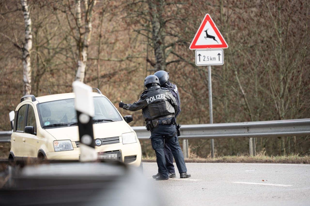 Polizeibeamte kontrollieren an einer Absperrung an der Kreisstraße 22, rund einen Kilometer von dem Tatort entfernt, an dem zwei Polizeibeamte durch Schüsse getötet wurden, ein Auto.