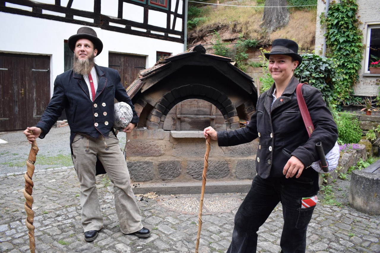 Wie ein Bild aus längst vergangener Zeit: Die Wandergesellen Maximilian und Johanna im Thüringer Denkmalhof Gernewitz in Kluft, mit Wanderstab und Gepäck. Gemeinsam mit rund 40 anderen Handwerkern, die ebenfalls auf der Walz sind, wollen sie hier bis zum 16. Juli ein gemeinnütziges Projekt in die Tat umsetzen.