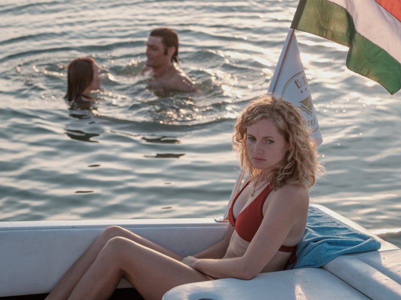 Maja (Sonja Gerhardt, l.) und Tamás (Stipe Erceg, M.) vergnügen sich im Wasser, während Catrin (Cornelia Gröschel, r.) betreten im Boot sitzen bleibt.