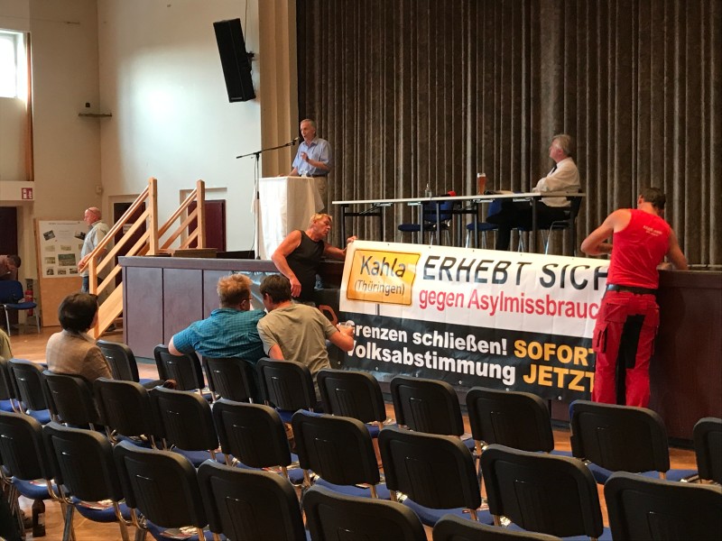 Zwei Männer bringen während der Rede von Martin Hohmann ein Plakat mit der Aufschrift Kahla erhebt sich gegen Asylmissbrauch an.