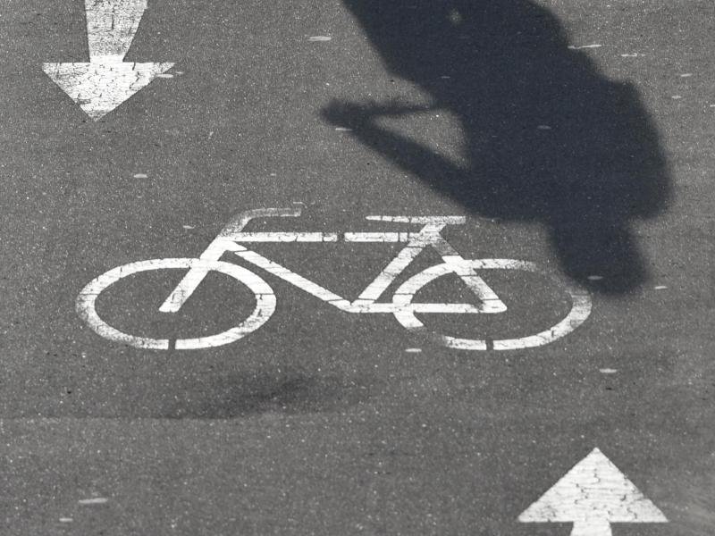 Der Schatten eines Radfahrers ist auf einem Radweg zu sehen.