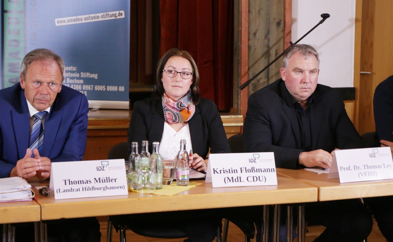 Auf dem Podium des IDZ sitzen der Landrat von Hildburghausen Thomas Müller (CDU), Landtagsabgeordnete Kerstin Floßmann (CDU) und Professor Dr. Thomas Ley, Leiter des Fachbereiches Polizei an der Fachhochschule für öffentliche Verwaltung in Meiningen. (v.l.n.r.)