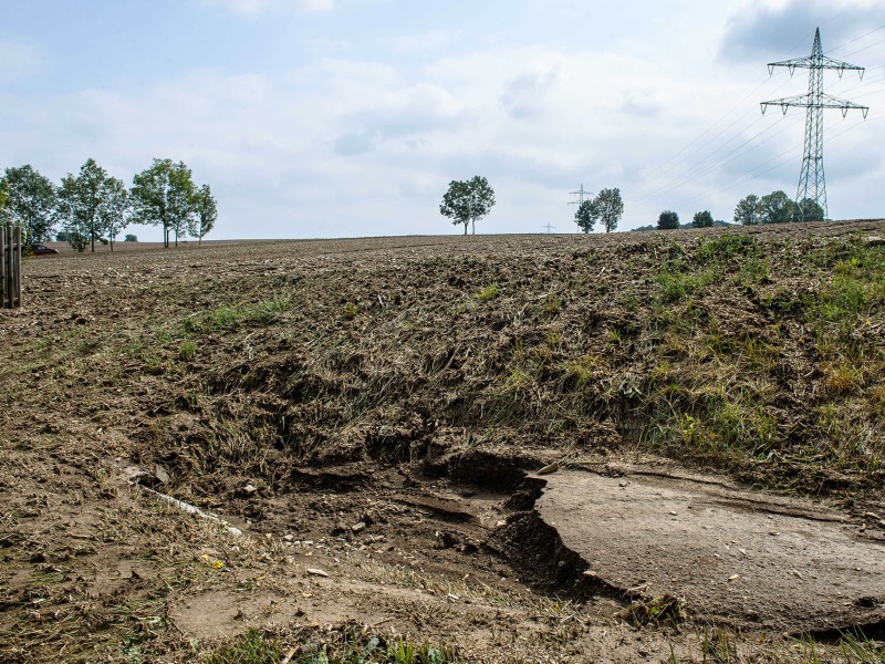 Eine Schlammlawine hat sich durch Tiefurt, einen Ortsteil von Weimar, gewälzt. Das Erdreich hatte sich am Freitagabend (17.08.2018) gelöst, als ein schweres Unwetter über die Region zog. Ein kurzer, aber heftiger Starkregen spülte das Material von einem Feld durch mehrere Grundstücke. Am Tag danach machten sich die Anwohner an die Aufräumarbeiten. Das Unwetter hatte auch an anderen Stellen in Weimar für Schäden gesorgt. So stürzte in der Innenstadt in einer Wohnung durch Wassereinbruch eine Zimmerdecke ein; von Bäumen brachen viele Äste ab, in einen davon fuhr ein Linienbus. Der Park an der Ilm sowie die Parks in Tiefurt und Belvedere wurden gesperrt.