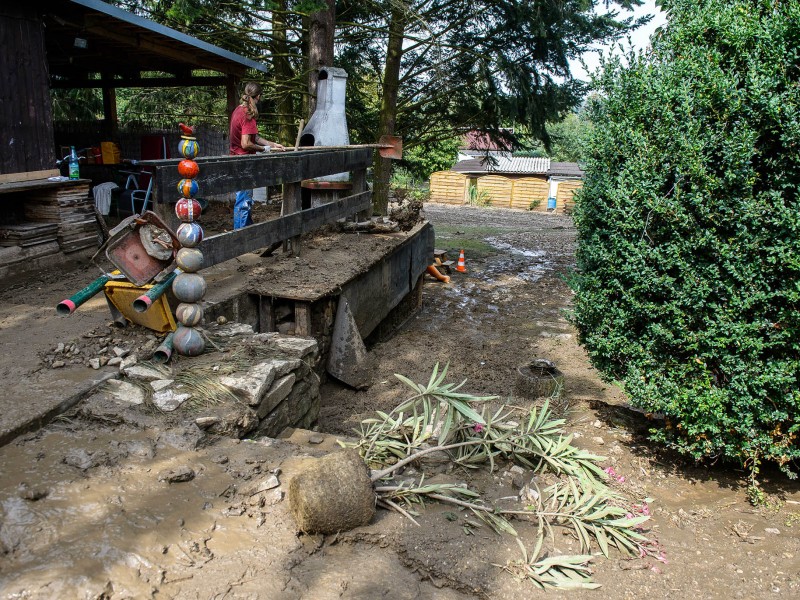 Eine Schlammlawine hat sich durch Tiefurt, einen Ortsteil von Weimar, gewälzt. Das Erdreich hatte sich am Freitagabend (17.08.2018) gelöst, als ein schweres Unwetter über die Region zog. Ein kurzer, aber heftiger Starkregen spülte das Material von einem Feld durch mehrere Grundstücke. Am Tag danach machten sich die Anwohner an die Aufräumarbeiten. Das Unwetter hatte auch an anderen Stellen in Weimar für Schäden gesorgt. So stürzte in der Innenstadt in einer Wohnung durch Wassereinbruch eine Zimmerdecke ein; von Bäumen brachen viele Äste ab, in einen davon fuhr ein Linienbus. Der Park an der Ilm sowie die Parks in Tiefurt und Belvedere wurden gesperrt.