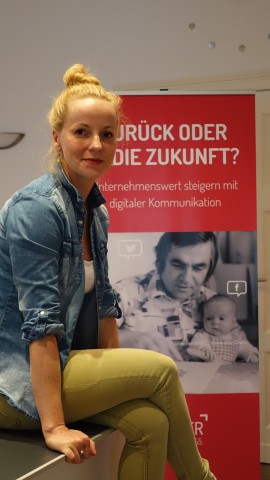 Nadine Reinhold vor einem Plakat, auf dem ein Foto von ihr als Baby mit ihrem Opa und Gründer der Firma Liebscher zu sehen ist.
