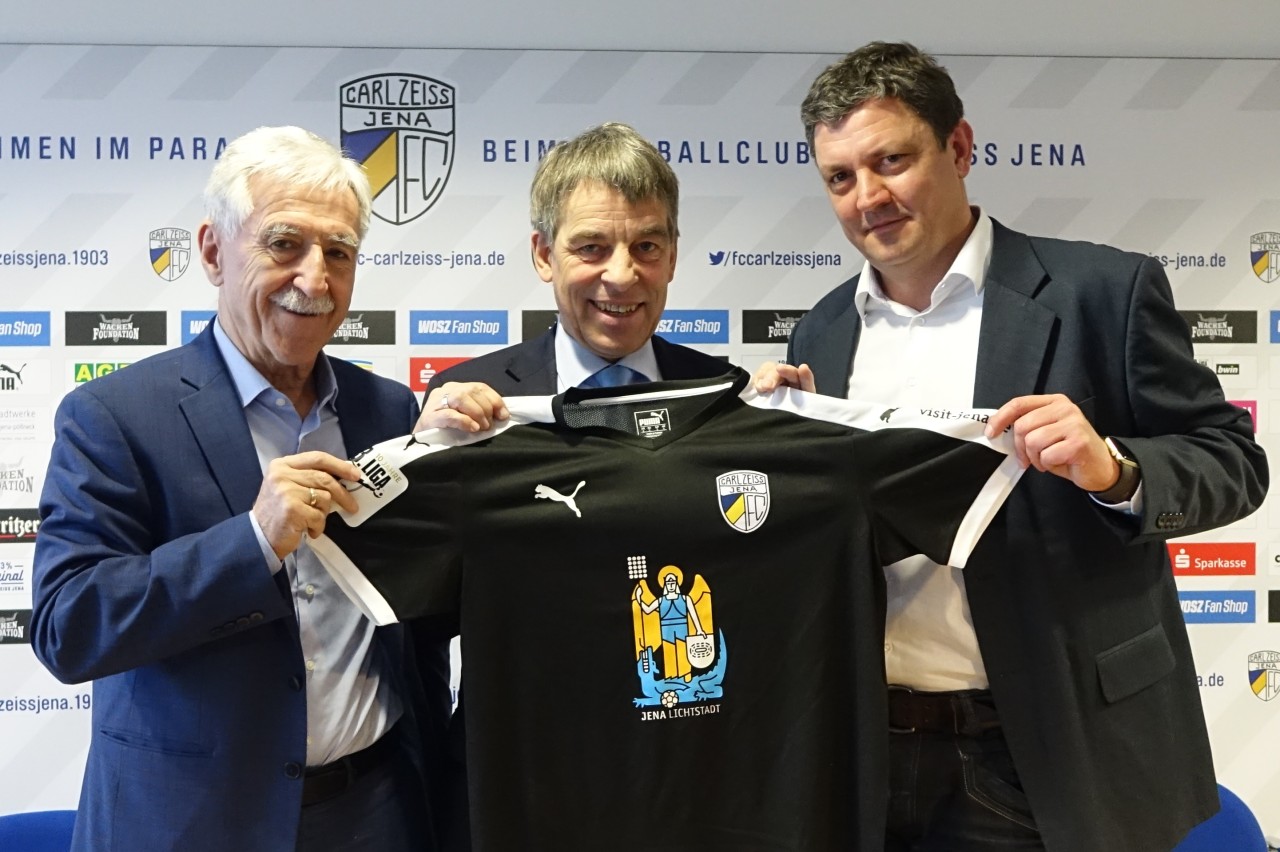 Klaus Berka, Präsident des FC Carl Zeiss Jena, Jenas Oberbürgermeister Albrecht Schröter und FCC-Geschäftsführer Chris Förster (v.l.) mit dem Sondertrikot anlässlich der Übergabe der neuen Flutlichtanlage im Ernst-Abbe-Sportfeld.