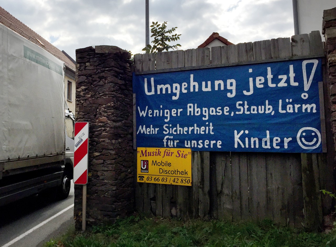  Ein Plakat mit der Aufschrift "Umgehung jetzt! Weniger Abgase, Staub, Lärm - Mehr Sicherheit für unsere Kinder" hängt in Großebersdorf.