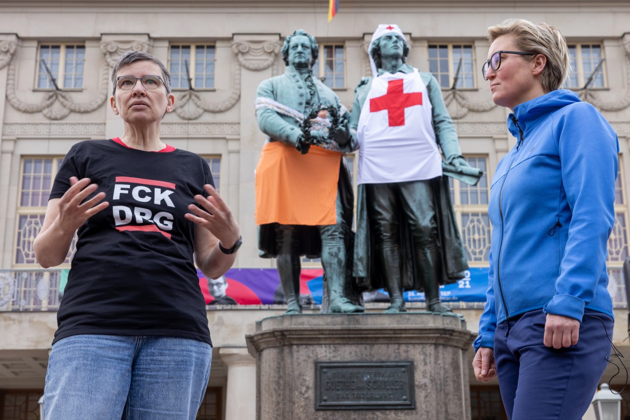 Susanne Hennig-Wellsow (rechts), Vorsitzende der Linke und Ellen Ost, Krankenpflegerin, sprechen vor den verkleideten Statuen von Goethe und Schiller in Weimar zu Personalbedarf und Arbeitsbedingungen in der Pflege. Die Verhüllungsaktion am Goethe- und Schiller-Denkmal soll auf den Pflegenotstand aufmerksam machen. 