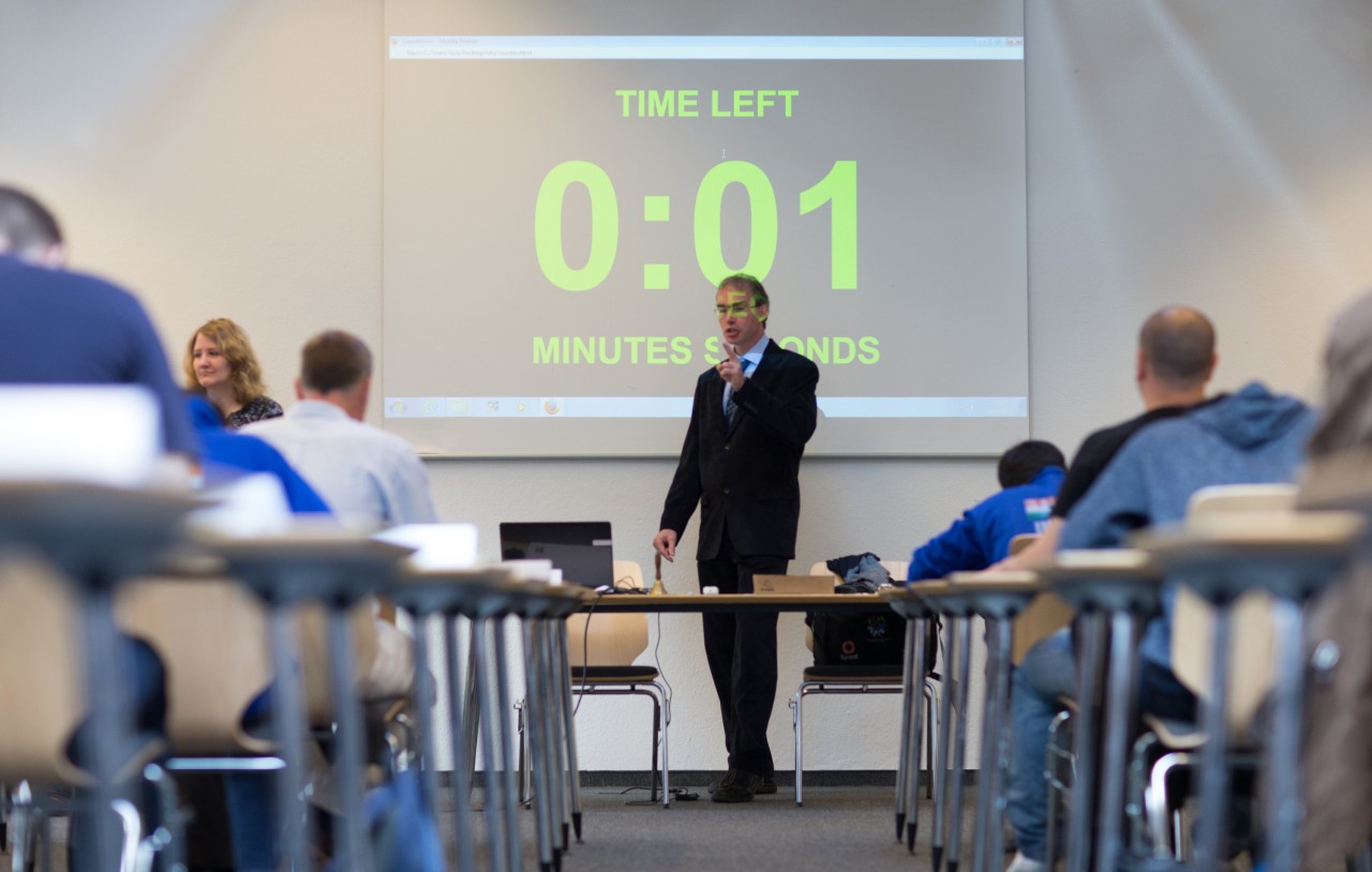 WM-Schiedsrichter Ralf Laue steht in einem Prüfungsraum vor einem countdown 