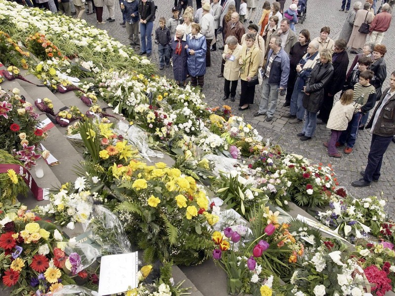 Menschen gedenken an der mit Blumen übersäten Treppe des Mariendoms in Erfurt der Opfer des Amoklaufs am Gutenberg-Gymnasium.