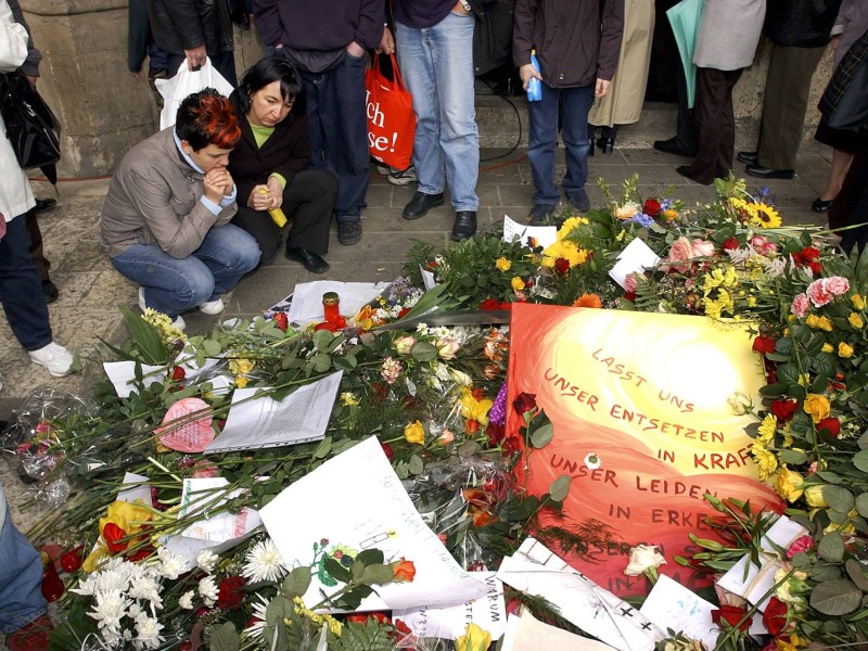 Trauernde Jugendliche stehen nach dem Amoklauf eines Schülers des Gutenberg-Gymnasiums in Erfurt vor Blumen und Kränzen.