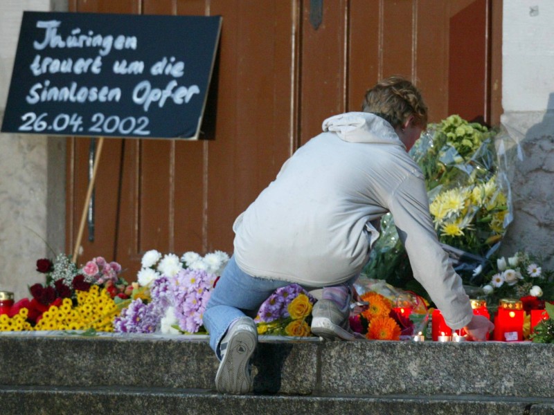 Eine junge Frau legt Blumen auf der Schwelle des Gutenberg-Gymnasiums ab. Der Amoklauf von Erfurt wird nie in Vergessenheit geraten.