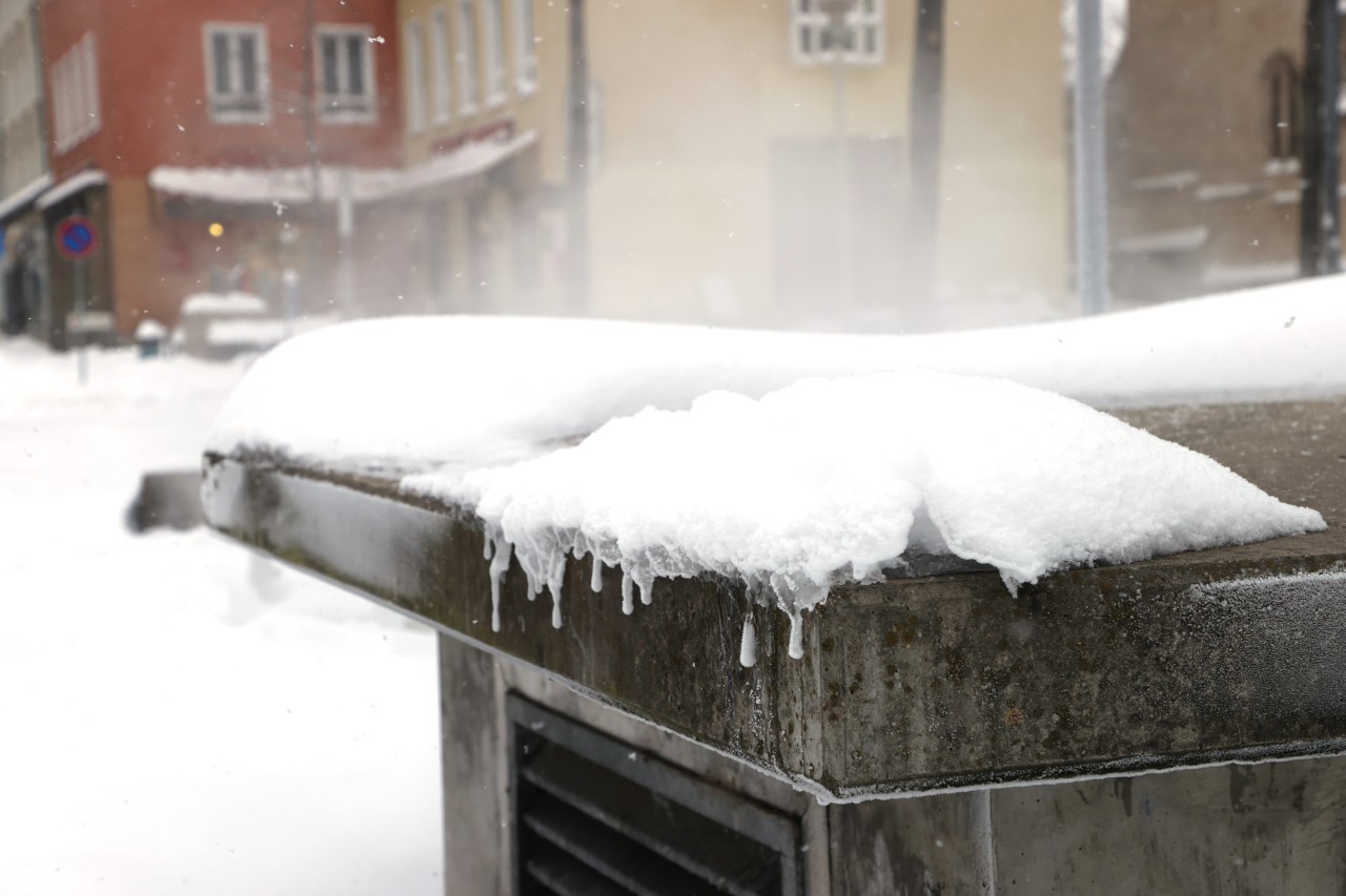 Heißer Dampf steigt aus einem mit Schnee bedeckten Lüftungsschacht im Zentrum von Jena.