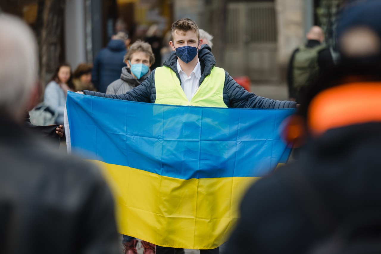 Ein Mann hält bei einer Kundgebung für Solidarität mit der Ukraine auf dem Erfurter Fischmarkt eine ukrainische Fahne.