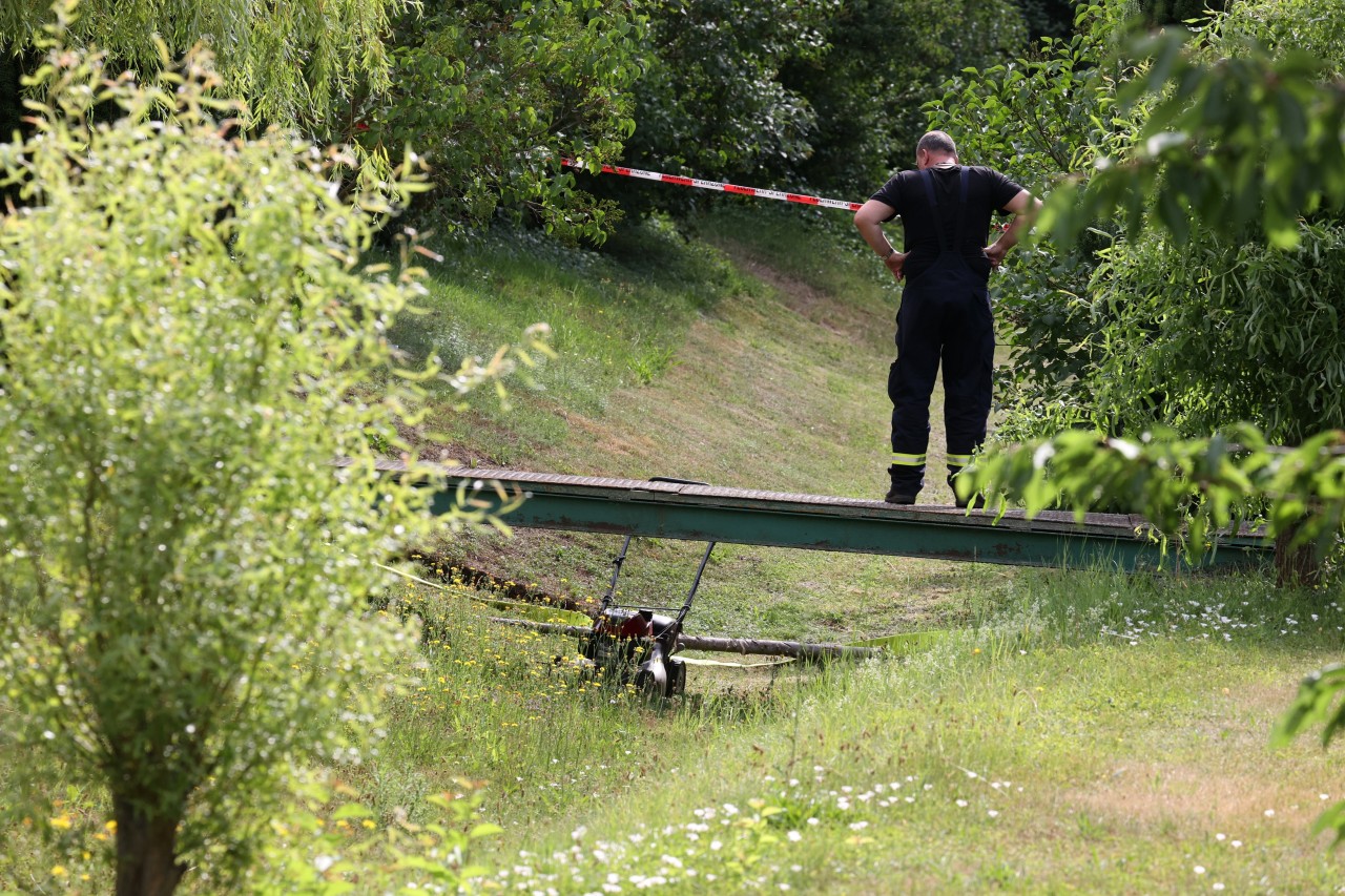 Weimarer Land: Ein Feuerwehrmann steht auf einer kleinen Brücke. Mit einer Kamerabefahrung wollen die Behörden Aufschluss über mögliche Ursachen für den schlimmen Unfall finden.