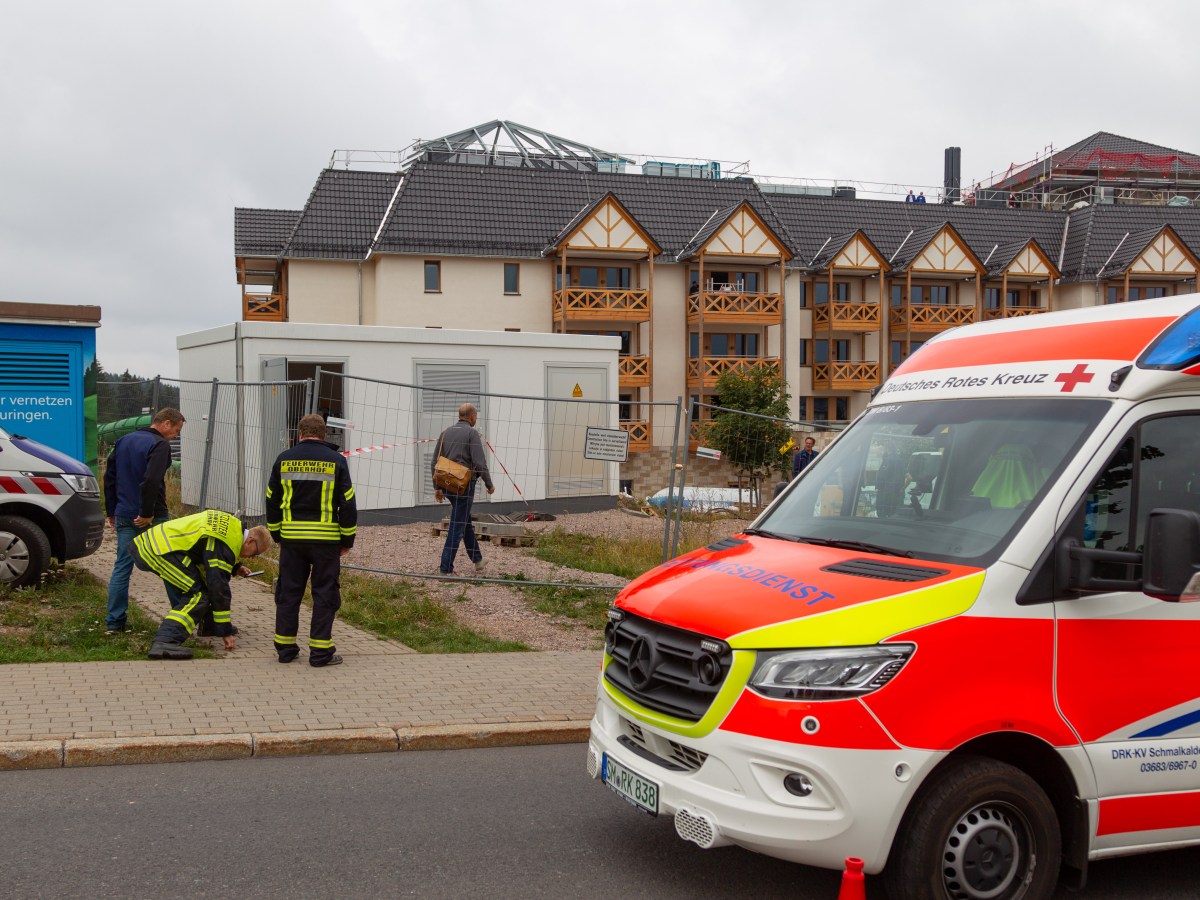 Rettungswagen steht vor Trafohäuschen mit Feuerwehrmännern davor
