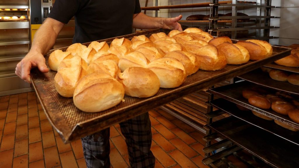 Bäcker holt frische Brötchen aus dem Ofen
