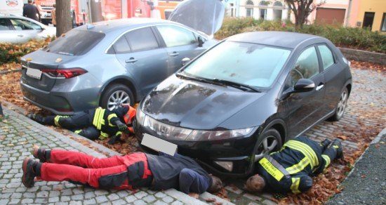 Feuerwehrleute kriechen unter ein Auto