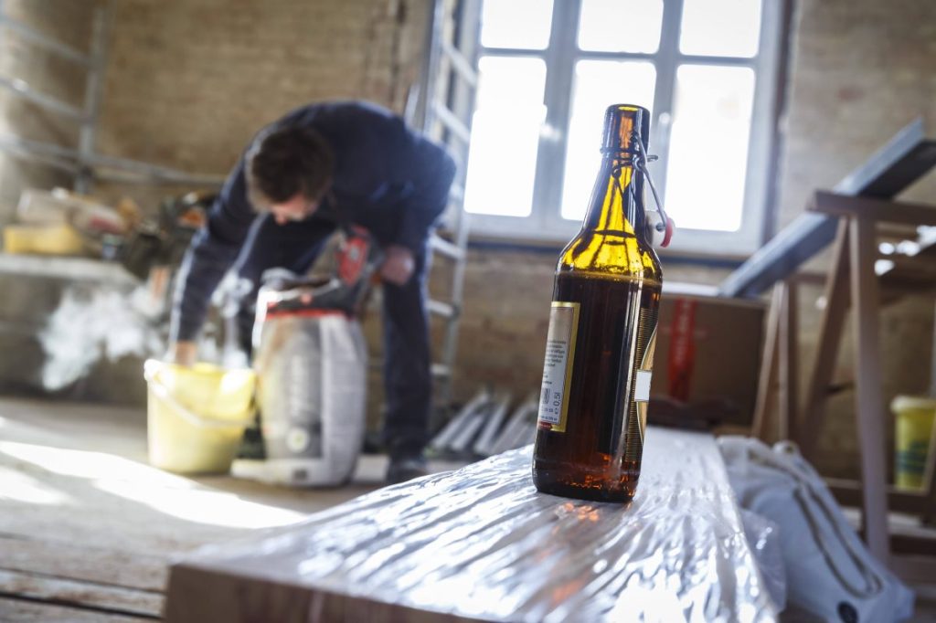 Bauarbeiter mit Bierflasche im Vordergrund