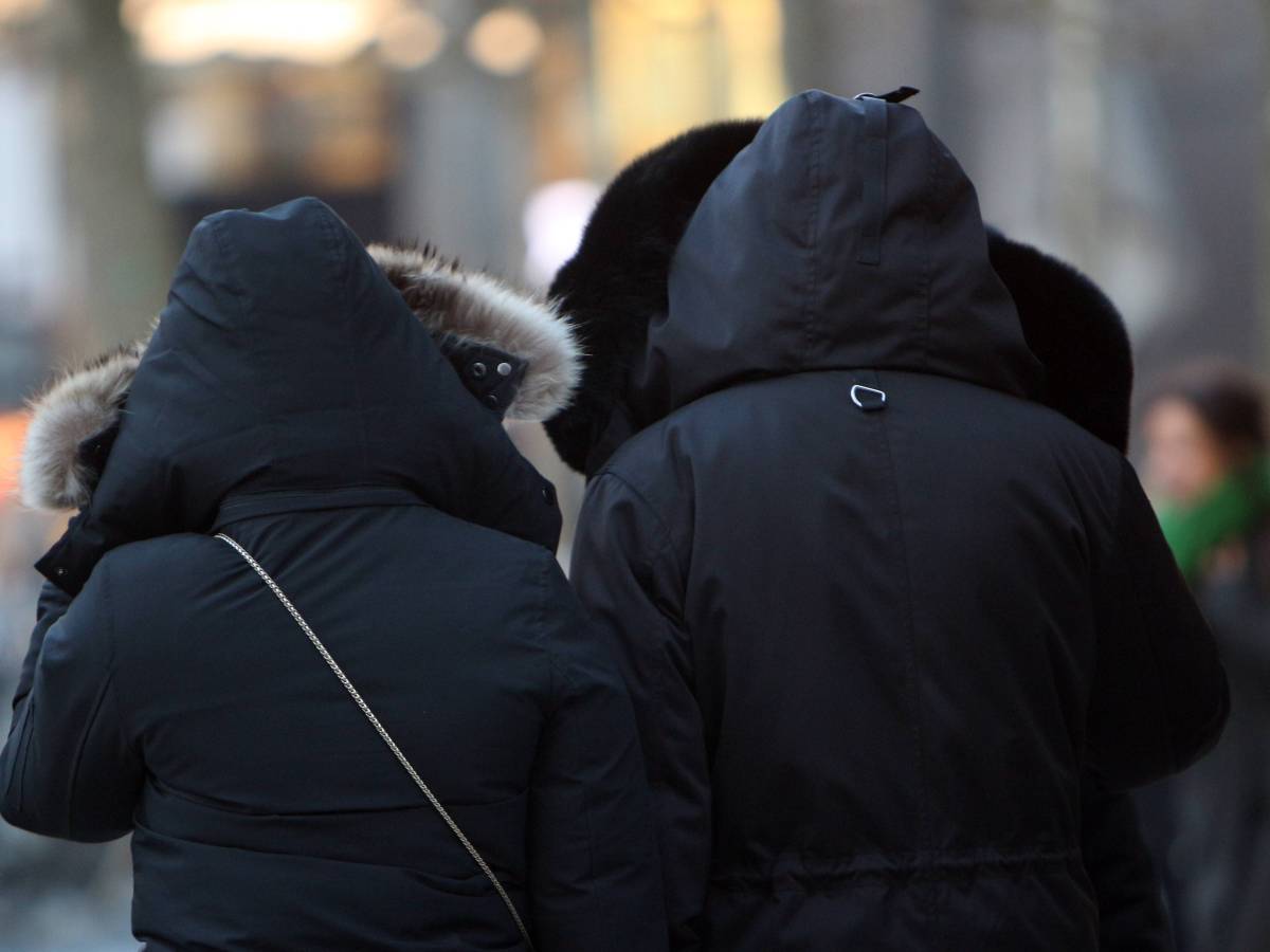 Personen versuchen sich vor der Eiskälte und den Sturmböen zu schützen in der Innenstadt Frankfurt